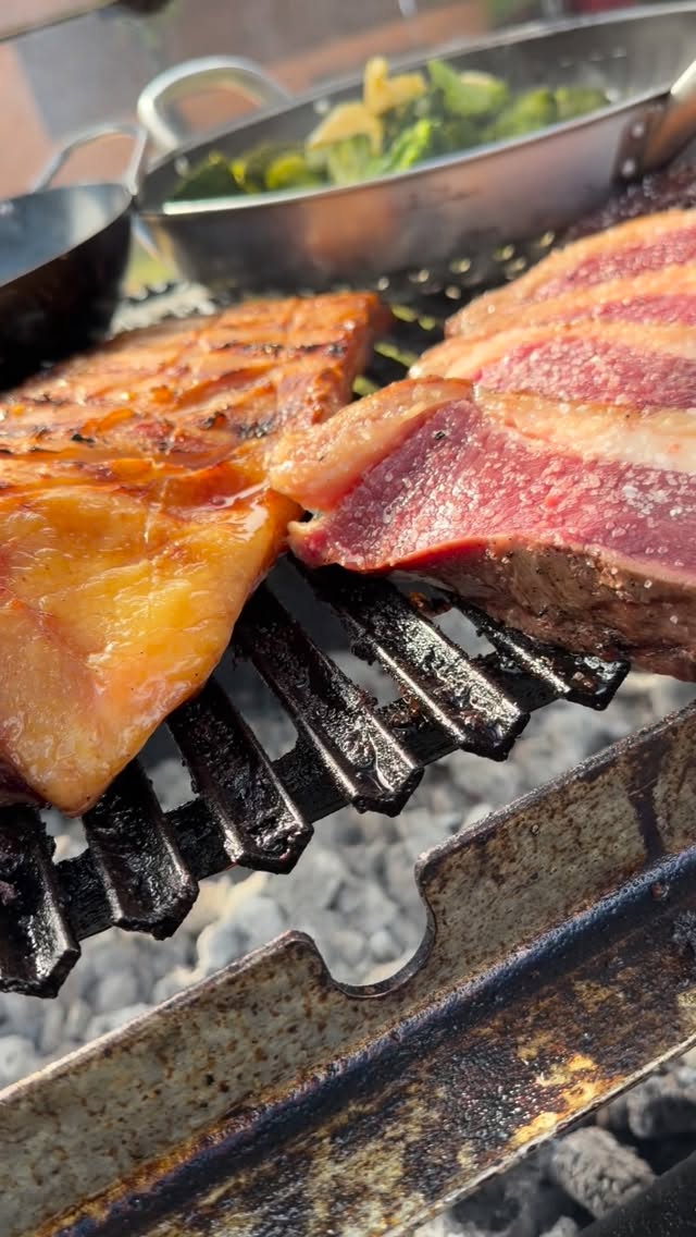 Peixe e cortes de carne sobre a chapa e a grelha em brasa.