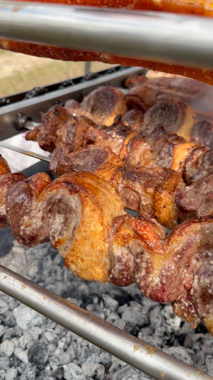Close de peças de carne douradas e crocantes recém-saídas da brasa.