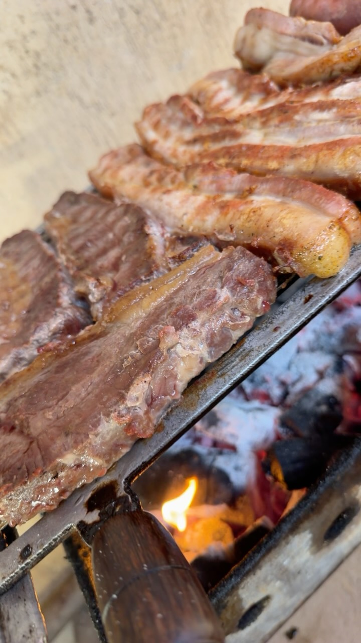 Costela bovina assando lentamente sobre a brasa.