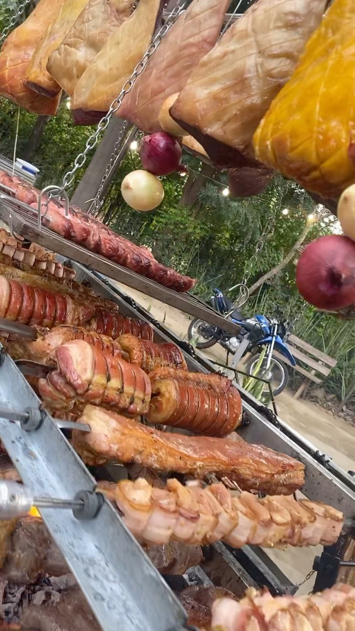 Espetos de linguiça, legumes e abacaxi assando na brasa.