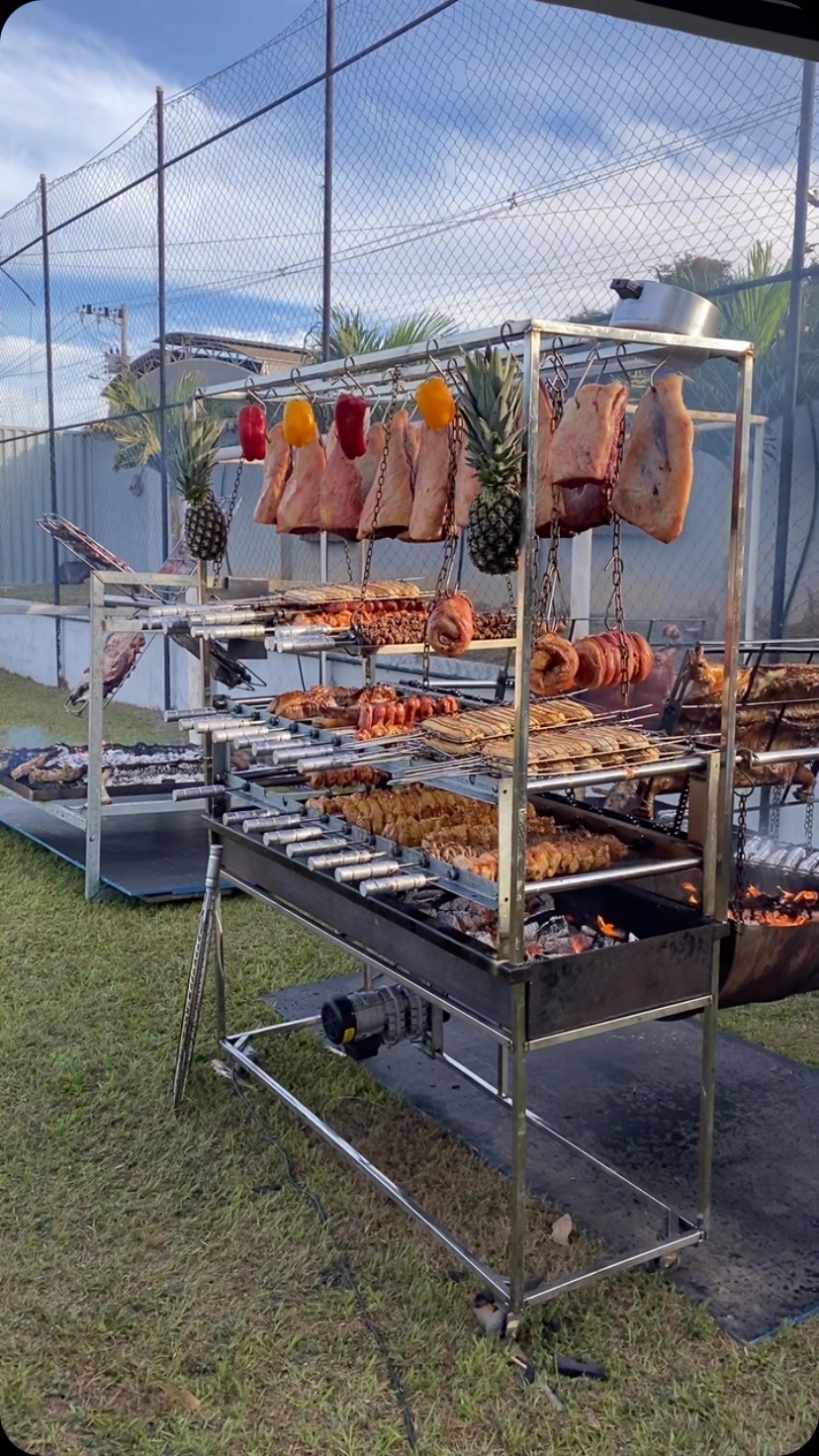 Grelha de parrilla carregada de espetos com carnes e legumes.